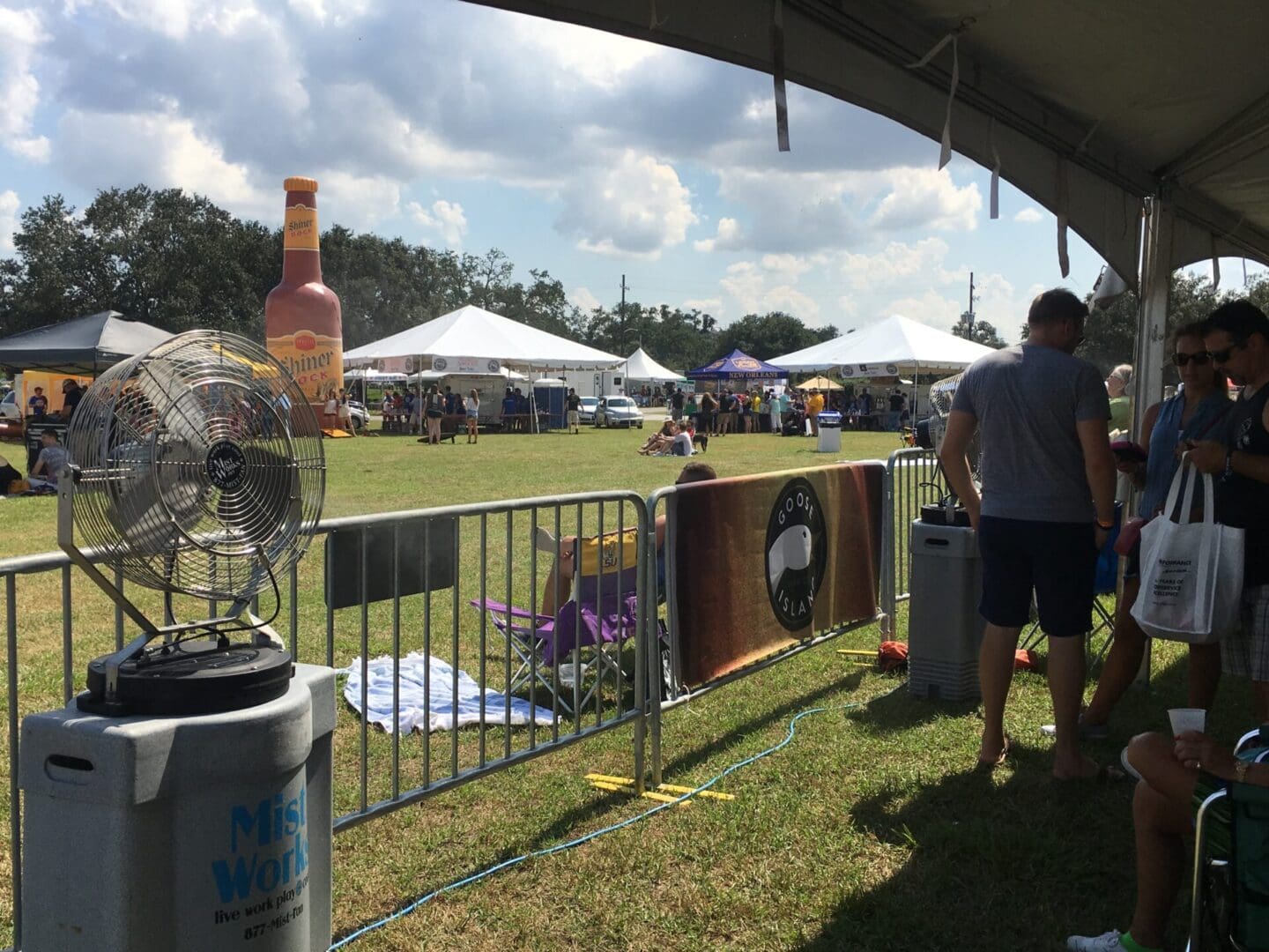 Outdoor festival with tents and giant bottle.